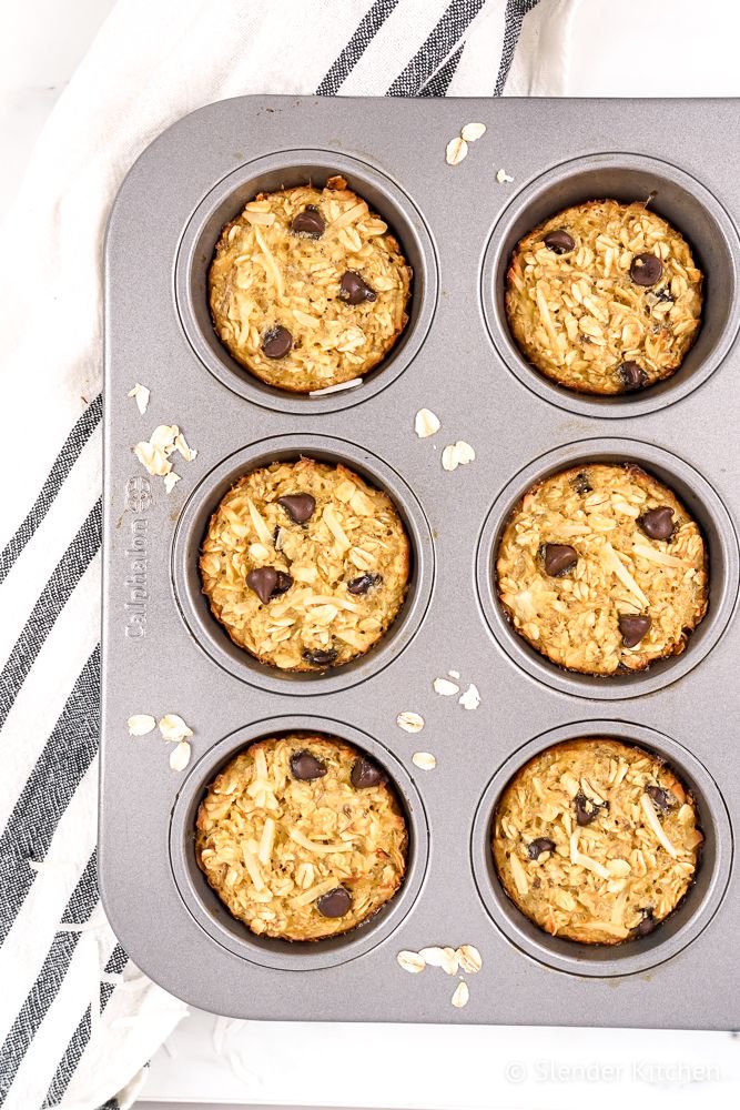 Baked oatmeal muffins with bananas, shredded coconut, and chocolate chips in a muffin tin.