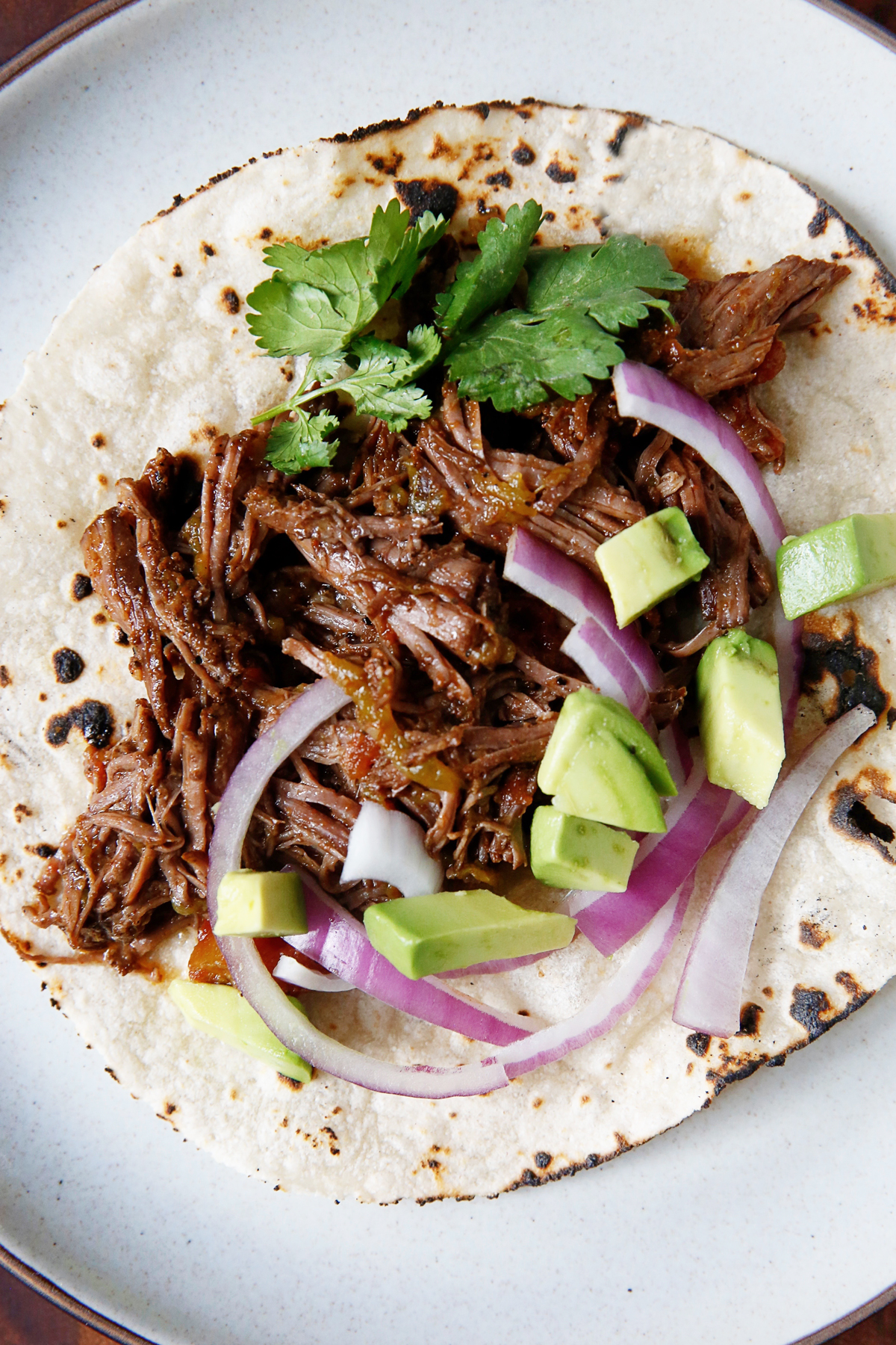 Barbacoa meat on a taco with toppings