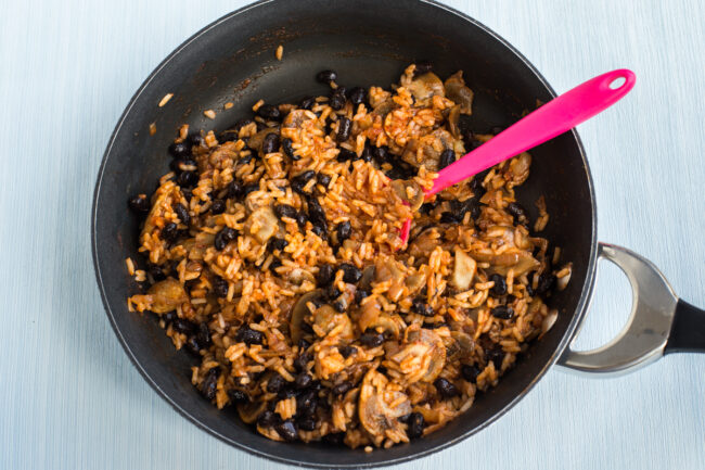 A mushroom, rice and black bean burrito filling cooking in a pan.