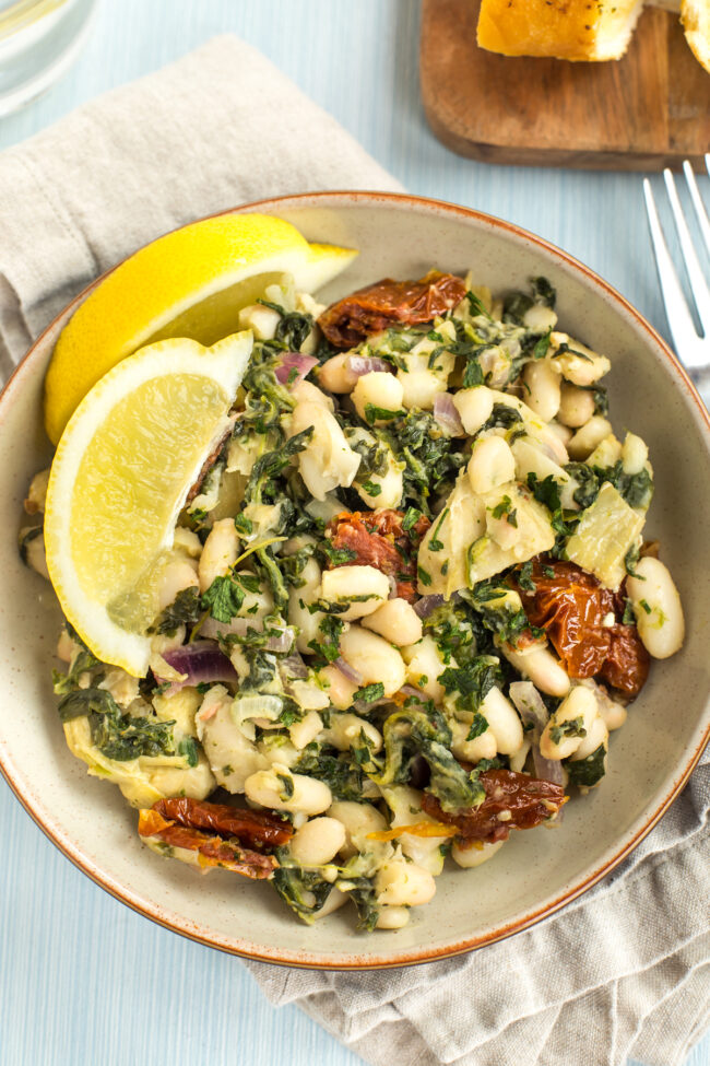 Portion of Tuscan beans with artichokes and spinach shot from above.