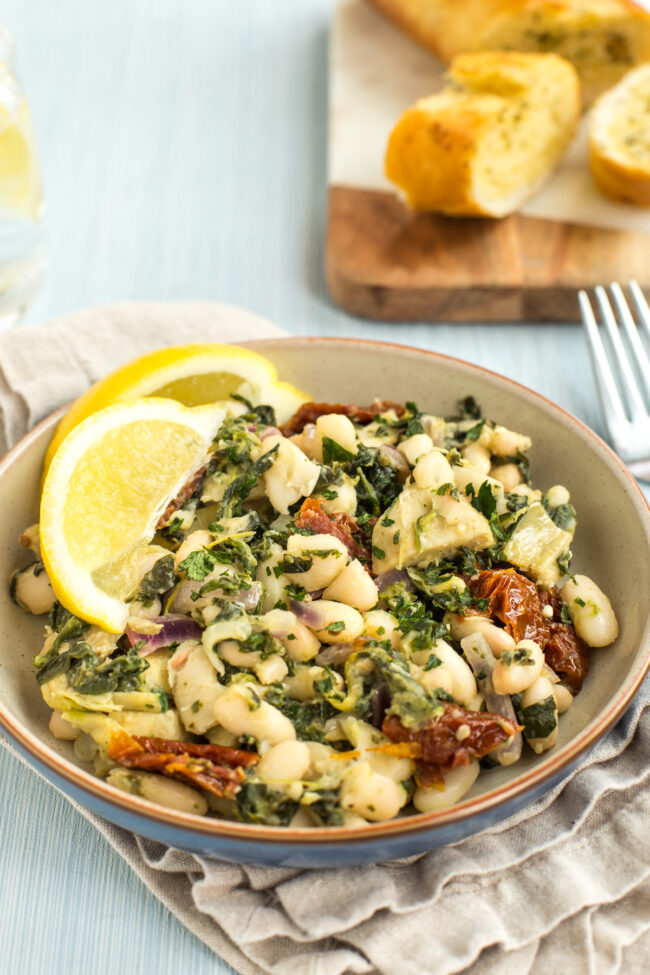 Portion of Tuscan beans with spinach and sun-dried tomatoes.