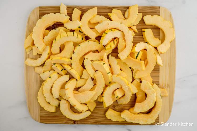 Cut delicata squash on a wooden board.