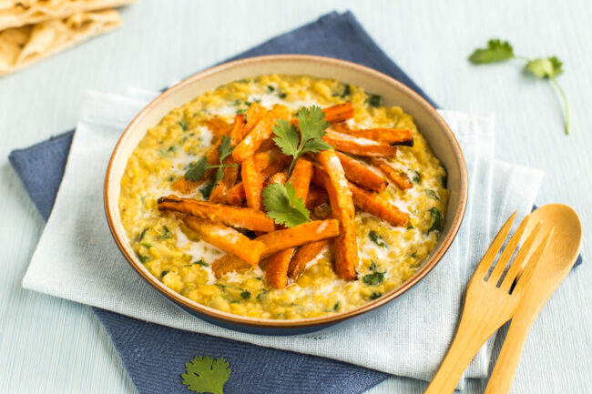 Portion of creamy dal in a bowl topped with roasted carrots and cilantro.