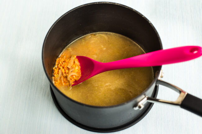 Red lentils and sauteed onions in a saucepan with lots of vegetable stock.