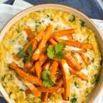 Portion of creamy lentil dal in a bowl topped with roasted carrots and cilantro.