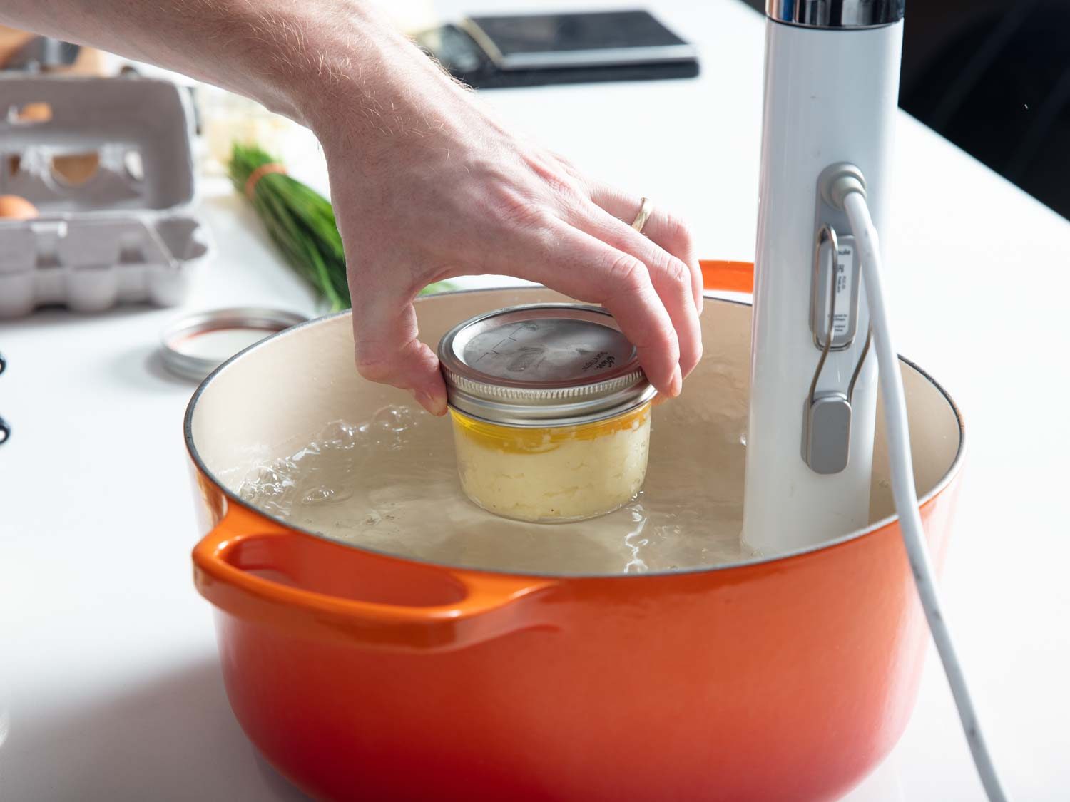 Placing a Mason into the sous vide water bath by hand.