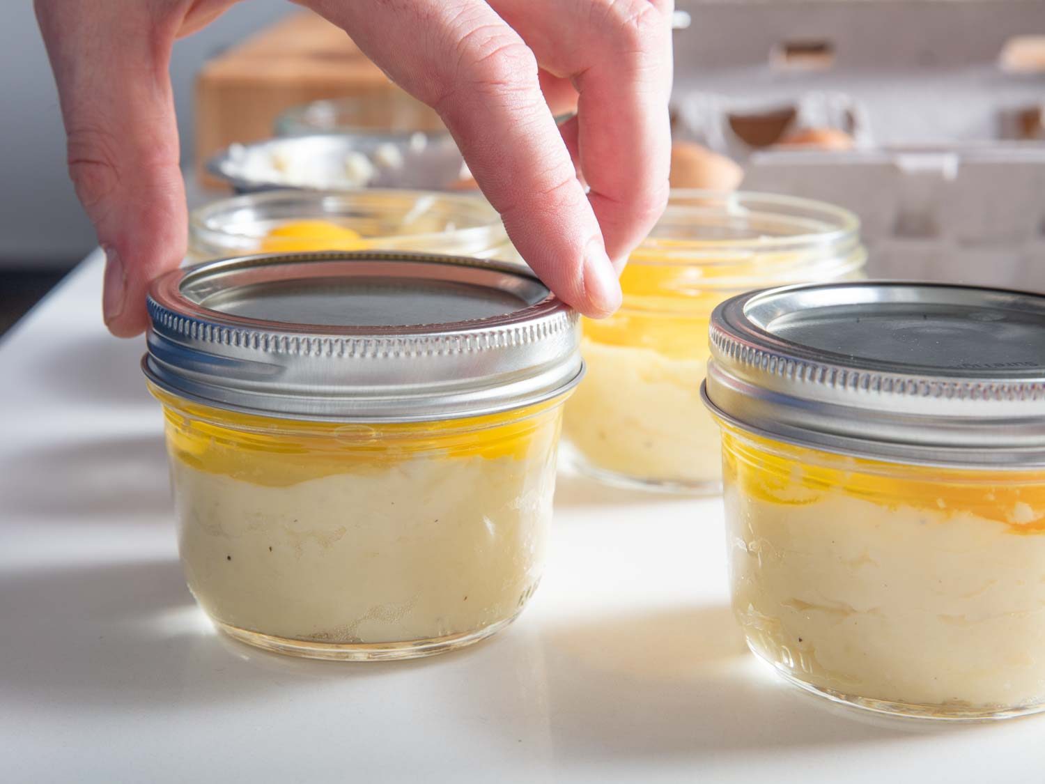 Sealing the lid of a Mason jar so that it is fingertip tight. Over-tightening the lids can cause the jars to crack.