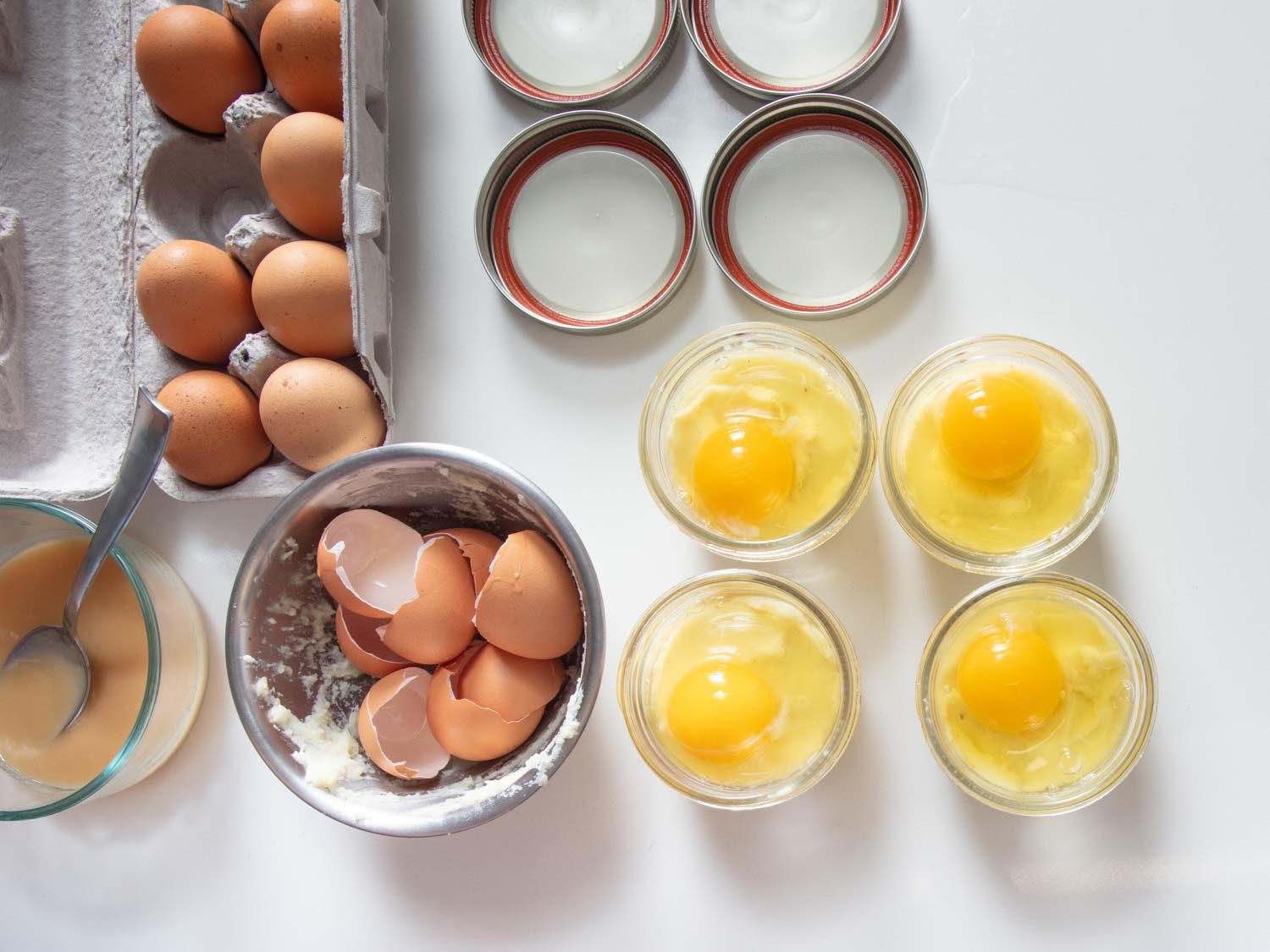 Overhead of four Mason jars, each filled with mashed potatoes and an uncooked egg.