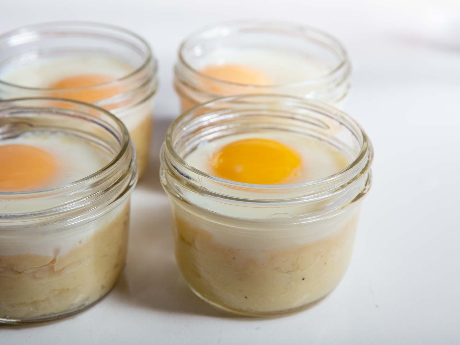 Closeup side view of four cooked mashed potato egg jars.