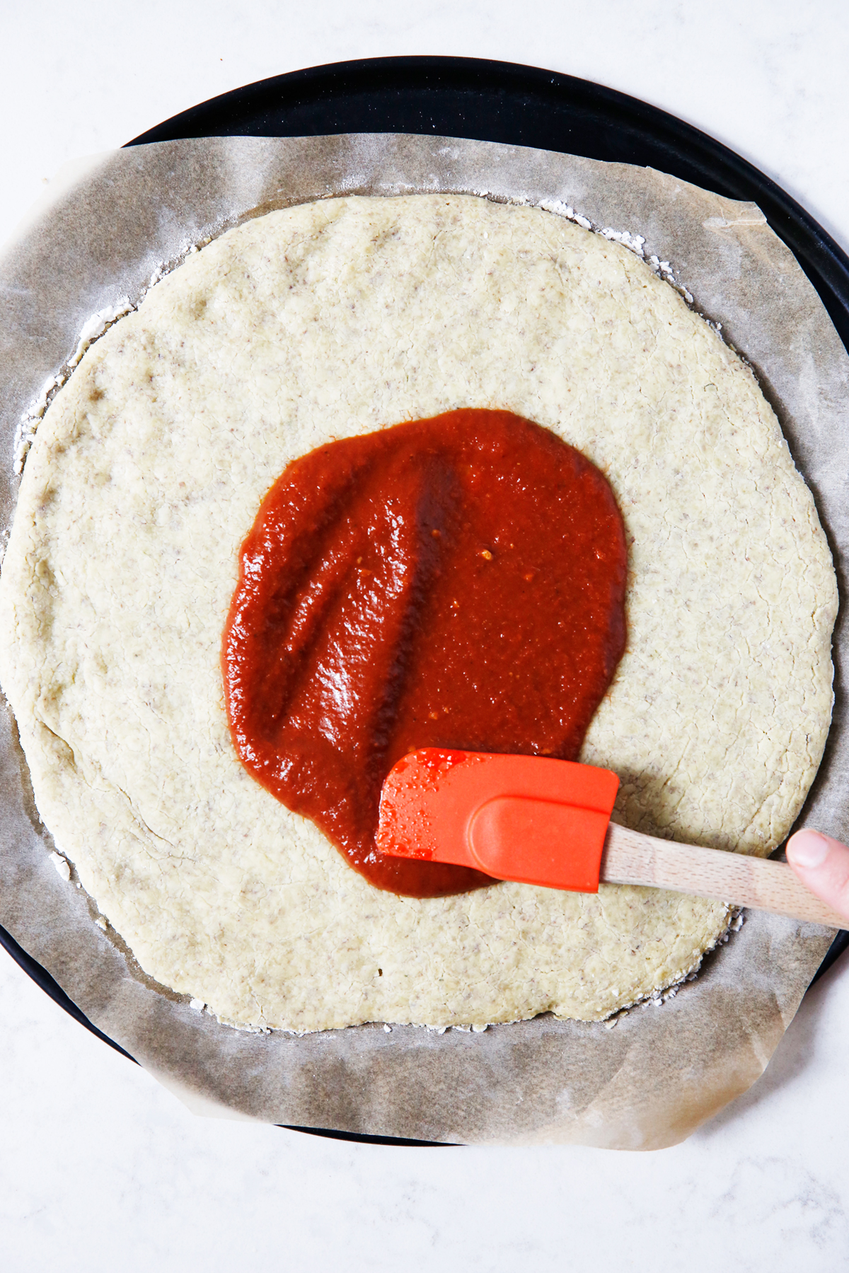 Spreading bbq sauce on pizza crust
