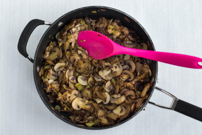 Garlicky mushrooms and leek cooking in a frying pan.