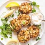 Crab meat on a white plate wtih lemon wedges and mayo dip