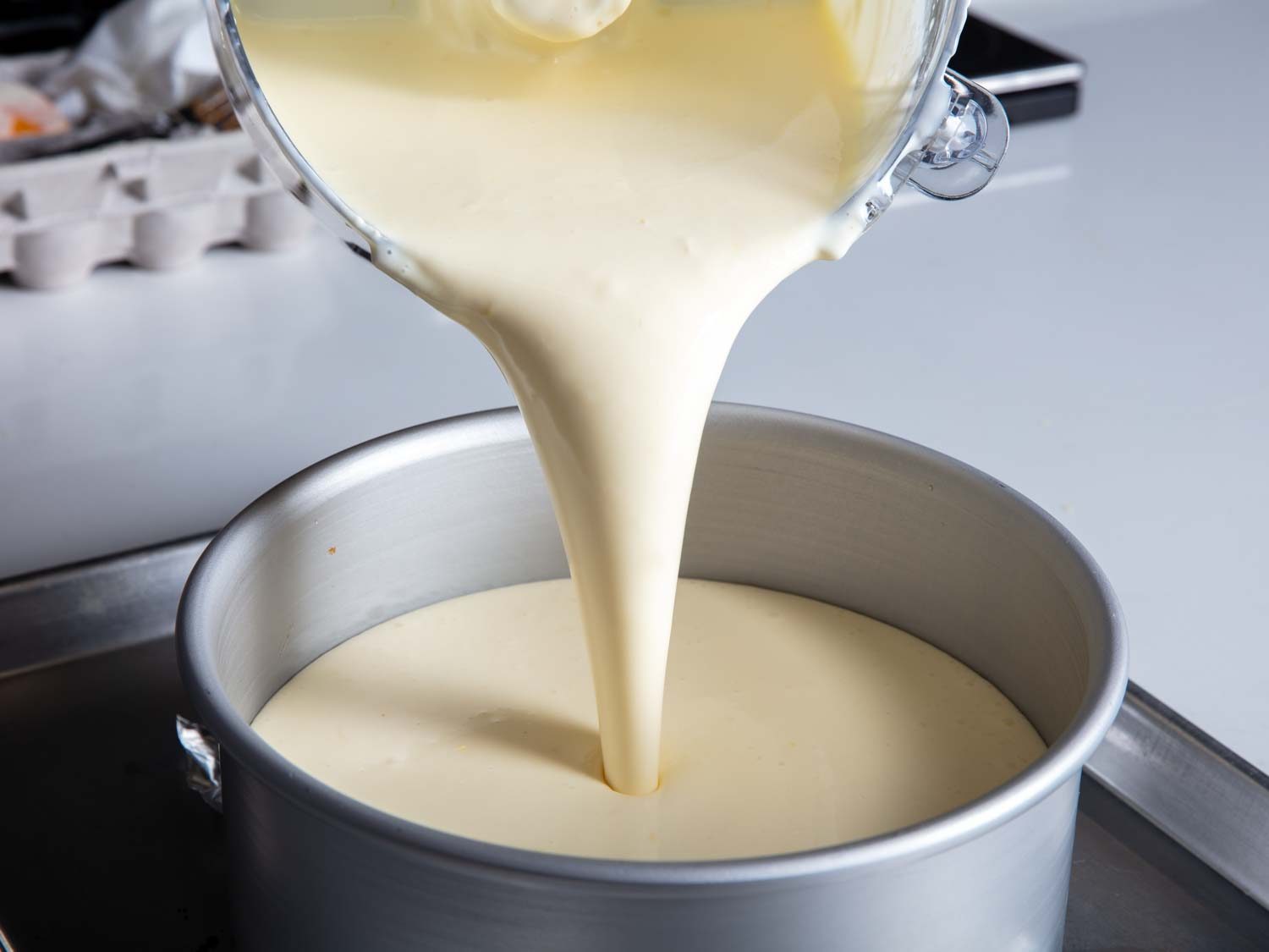 pouring the creamy cheesecake batter into the prepared pan