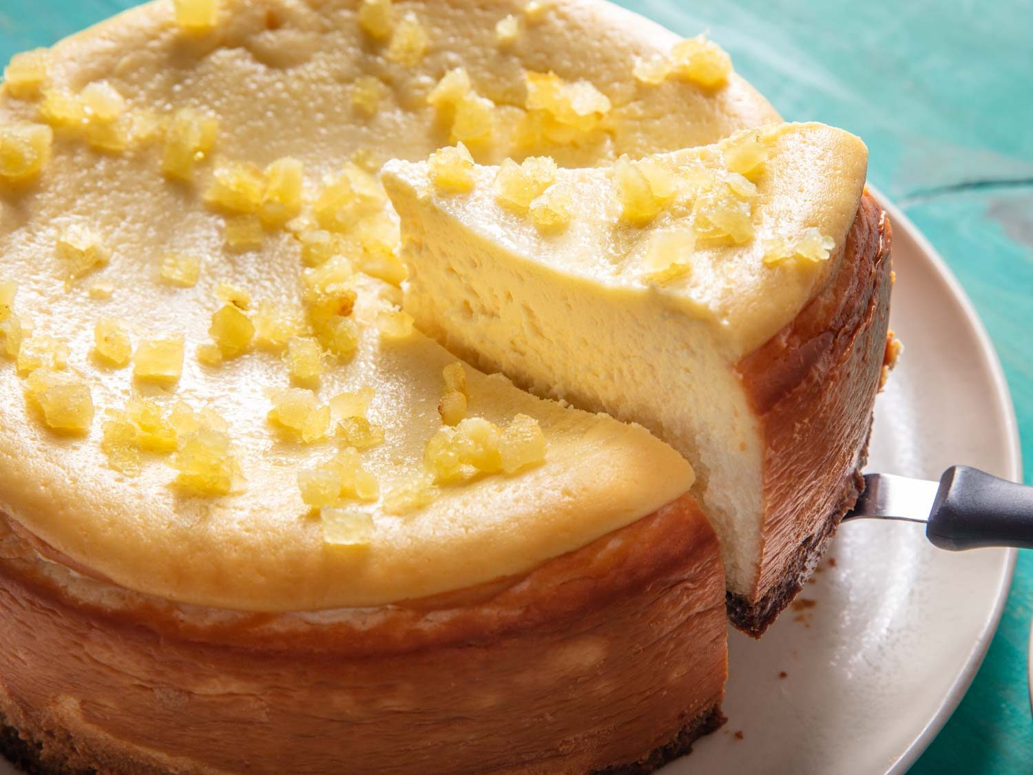 Detail of a lemon cheesecake with a single slice being lifted from the whole