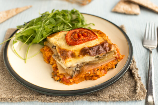 A portion of vegetarian moussaka on a plate served with rocket.