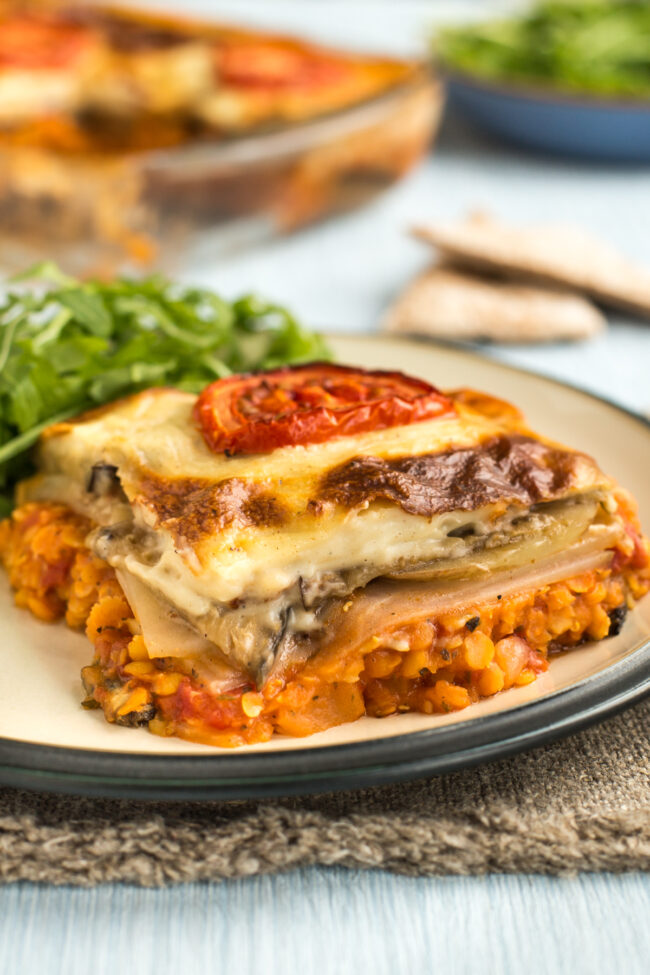 A portion of vegetarian moussaka on a plate served with rocket.