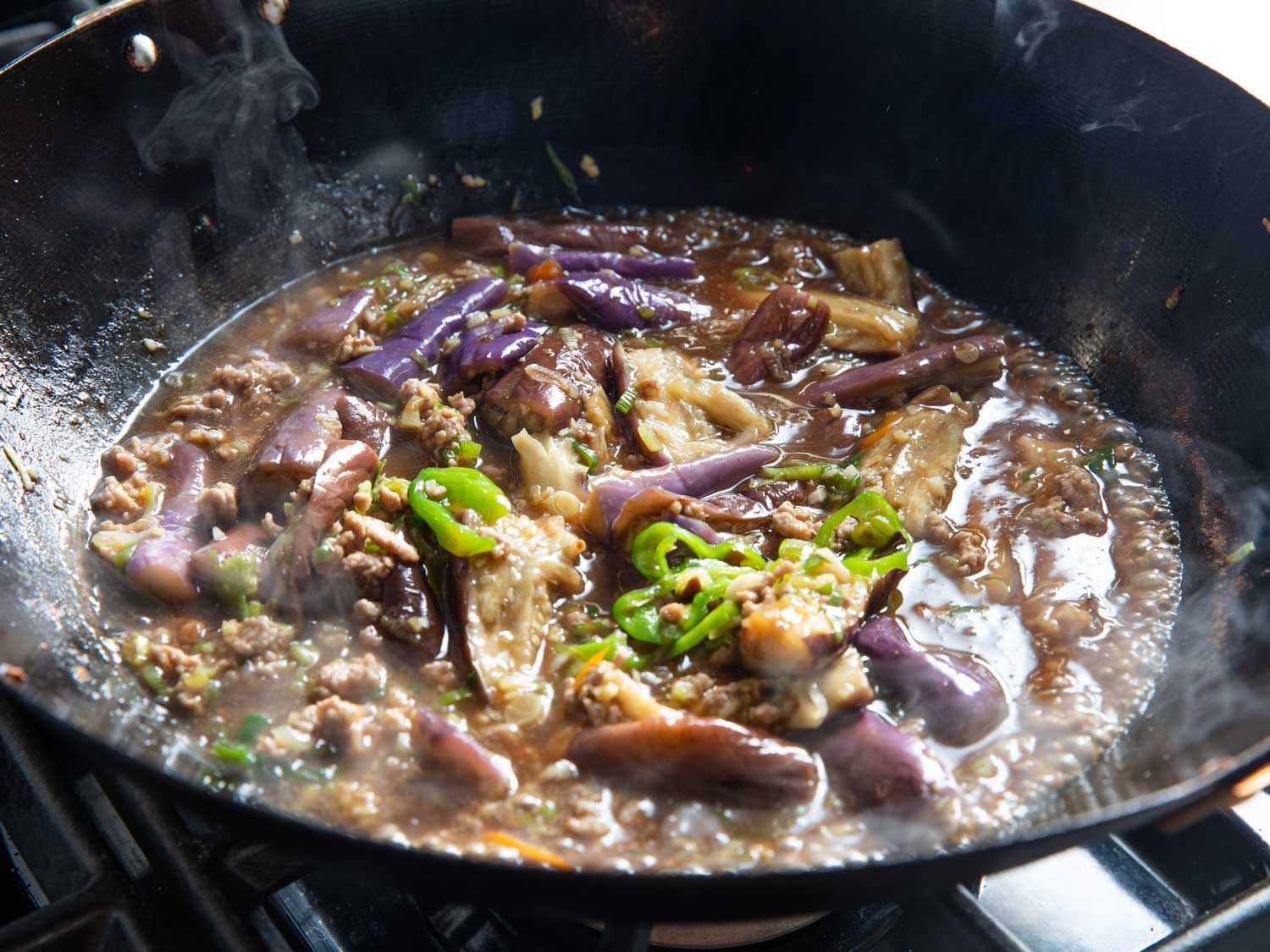 Sichuan eggplant simmering in a wok