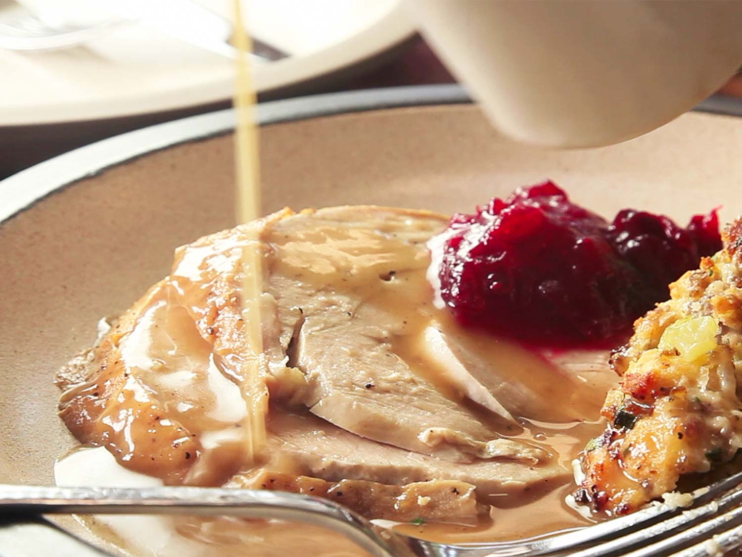 Slices of roast turkey being drizzled with gravy