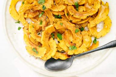 Roasted delicata squash with brown sugar and cinnmon on a white plate.