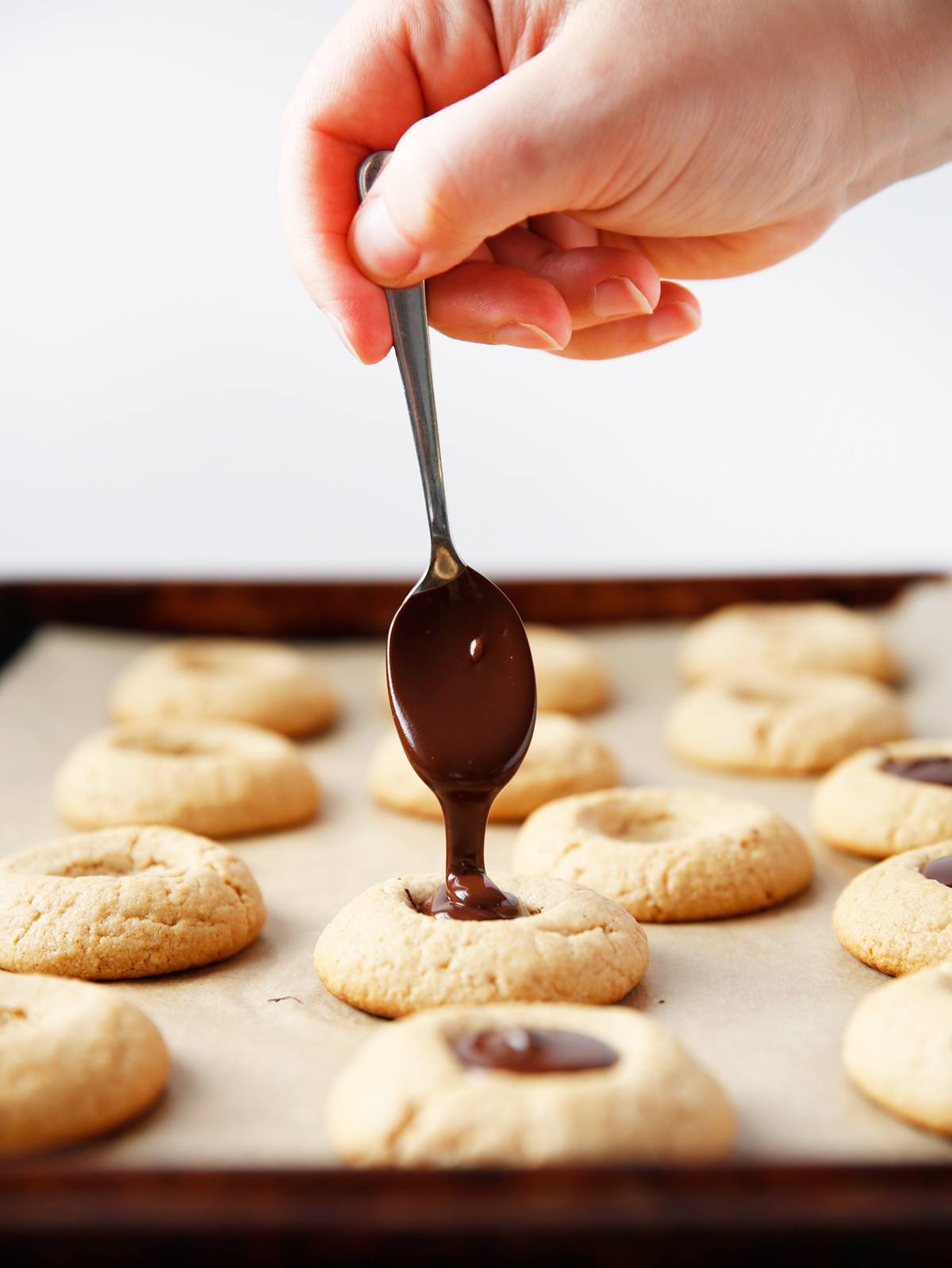 Spooning chocolate into gluten free peanut butter cookies