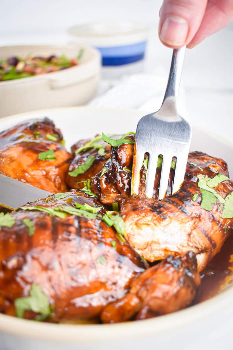 Broiled Chicken Thighs with a spicy barbecue sauce on a plate with cilantro.