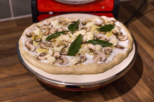 An uncooked mushroom pizza inside the Optima Pizza Express Napoli countertop pizza oven.