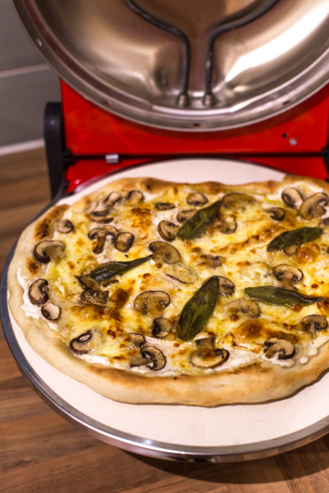 A cooked mushroom pizza inside a countertop pizza oven.