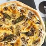 A crispy white pizza topped with mushrooms and sage.