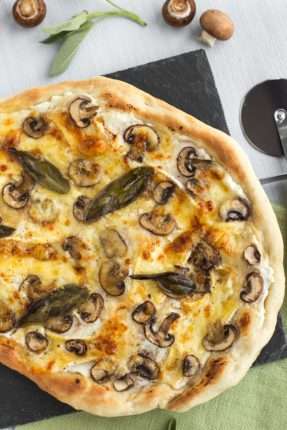 A crispy white pizza topped with mushrooms and sage.