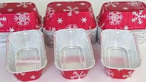 A set of red and white foil baking pans with snowflakes on them.